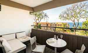 Terassi, jossa on istuinryhmä ja näkymä merelle, pöytä ja kaksi viinilasia. (Tekoälyn luoma teksti)