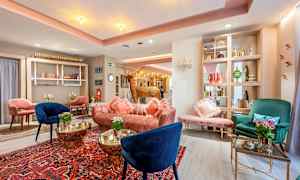 Tyylikkäästi sisustettu hotellin aula, jossa on värikkäitä nojatuoleja, sohvia ja koristeellisia yksityiskohtia. (Tekoälyn luoma teksti)