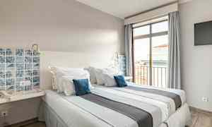 Hotellihuone, jossa on kaksi sänkyä, siniset koristeelliset tyynyt ja ikkunanäkymä. (Tekoälyn luoma teksti)