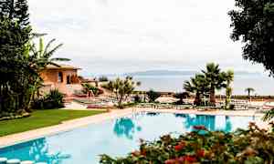 Kuva ulkoaltaasta, jota ympäröivät vehreys, aurinkotuolit ja rakennus taustalla. (Tekoälyn luoma teksti)