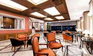 Tyylikäs lounge, jossa on punaiset tuolit, marmori lattia ja puuyksityiskohtia katossa. (Tekoälyn luoma teksti)