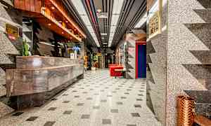 Hotellin aula marmorisella sisustuksella, vastaanottoalueella ja punaisilla istuinkalusteilla. (Tekoälyn luoma teksti)