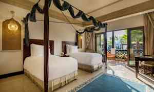 Makuuhuone, jossa on kaksi yhden hengen vuodetta, tummia puuhuonekaluja ja suuret lasiovet, jotka avautuvat terassille. (Tekoälyn luoma teksti)