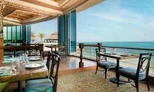 Ravintola, josta on näkymä merelle, lasiseinät ja tyylikkäät pöytäkatteet. (Tekoälyn luoma teksti)