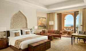 Hotellihuone, jossa on parivuode, istuinalue, kirjoituspöytä ja parveke merinäköalalla. (Tekoälyn luoma teksti)