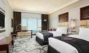 Hotellihuone, jossa kaksi sänkyä, kirjoituspöytä ja näkymä merelle. Seinäkoriste ja tyylikäs sisustus. (Tekoälyn luoma teksti)