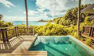 Näkymä puiselta terassilta ja altaalta trooppiseen puutarhaan ja merelle. (Tekoälyn luoma teksti)