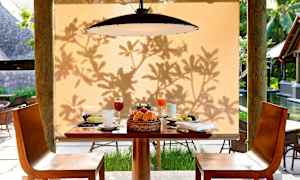 Aamiainen tarjoillaan pöydällä beigeellä taustalla, varjoja lehvästöstä. (Tekoälyn luoma teksti)