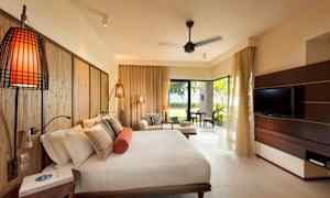 Hotellihuone, jossa on suuri sänky, sohva ja televisio sekä näköala vehreään puutarhaan. (Tekoälyn luoma teksti)