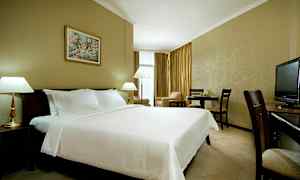 Hotellihuone, jossa on suuri pedattu sänky, lamput, ruokapöytä ja televisio. (Tekoälyn luoma teksti)