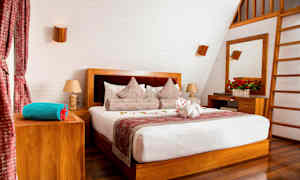 Tyylikäs makuuhuone, jossa on parivuode, puuelementtejä ja koristellut tyynyt. (Tekoälyn luoma teksti)