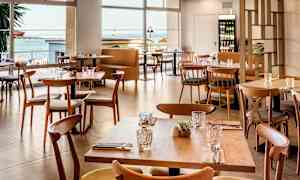 Modernit puupöydät ja -tuolit ravintolassa merinäköalalla. (Tekoälyn luoma teksti)