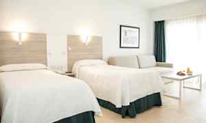 Hotellihuone, jossa on kaksi sänkyä, sohva, pöytä ja aamiaistarjoilu. (Tekoälyn luoma teksti)