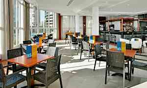 Ravintola, jossa on pöytiä ja tuoleja vaalealla lattialla. (Tekoälyn luoma teksti)