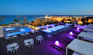 Ulkouima-allasalue, josta on näkymä merelle ja pienvenesatamaan, valaistus pimeässä. (Tekoälyn luoma teksti)