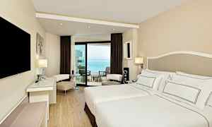 Moderni hotellihuone, jossa on parisänky ja parveke merinäköalalla. (Tekoälyn luoma teksti)