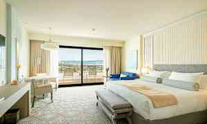 Hotellihuone, jossa on parivuode, istuinalue ja parveke näköalalla. (Tekoälyn luoma teksti)