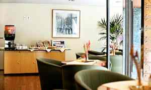 Kahviasema ja istuinryhmä hotellissa tai kahvilassa. Kahviautomaatti ja välipaloja on asetettu kaapin päälle. (Tekoälyn luoma teksti)