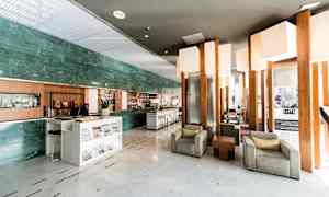 Hotellin aula, jossa on istuinryhmiä ja vastaanottotiski. (Tekoälyn luoma teksti)