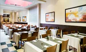 Ruokasali, jossa on katettuja pöytiä ja seinillä ripustettuja tauluja. (Tekoälyn luoma teksti)