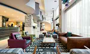 Hotellin aula, jossa on istuma-alueita, vastaanotto ja koristeita. (Tekoälyn luoma teksti)