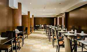 Ravintolatila, jossa on rivejä pöytiä ja tuoleja, katettu vieraille. (Tekoälyn luoma teksti)