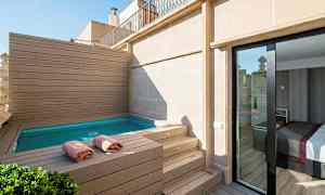 Terassi, jossa pieni uima-allas, ympärillä puupaneeleja, pyyhkeitä reunoilla ja lasiovi, joka johtaa huoneeseen. (Tekoälyn luoma teksti)