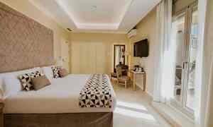 Hotellihuone, jossa on suuri parivuode, televisio seinällä ja kirjoituspöytä tuoleineen. (Tekoälyn luoma teksti)