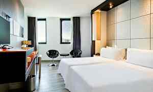 Tyylikäs hotellihuone, jossa on kaksi yhden hengen vuodetta, minimalistinen sisustus ja suuret ikkunat, joista pääsee luonnonvaloa. (Tekoälyn luoma teksti)