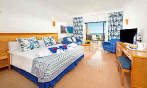 Hotellihuone, jossa parisänky, oleskelutila ja terassi. Näkymä näyttää meren. (Tekoälyn luoma teksti)