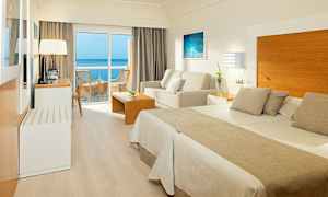 Hotellihuone, jossa parisänky, oleskelutila ja parveke merinäköalalla. (Tekoälyn luoma teksti)