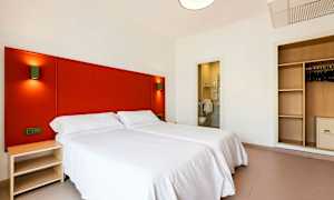 Hotellihuone, jossa kaksi yhden hengen vuodetta, vaatekaappi ja avoin kylpyhuone. (Tekoälyn luoma teksti)