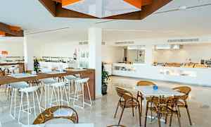 Moderni ravintola, jossa valkoisia pöytiä ja tuoleja. Buffet-osio näkyy taustalla. (Tekoälyn luoma teksti)