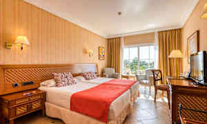 Kuva hotellihuoneesta, jossa on kaksi sänkyä, tuoli ja pöytä sekä televisio. (Tekoälyn luoma teksti)