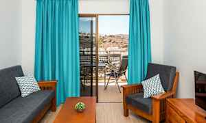 Olohuone, jossa tummat huonekalut, siniset verhot ja näkymä parvekkeelta. (Tekoälyn luoma teksti)