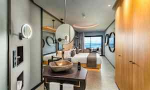 Tyylikkään hotellihuoneen sisustus, johon kuuluu sänky, kylpyhuone ja merinäköala. (Tekoälyn luoma teksti)