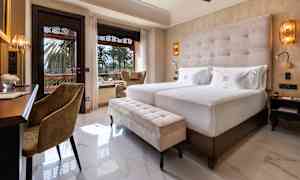 Hotellihuone, jossa kaksi vuodetta, istuimia ja näkymä puutarhaan. (Tekoälyn luoma teksti)