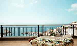 Aurinkotuoleja terassilla, näkymä merelle ja satamaan. (Tekoälyn luoma teksti)