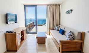 Hotellihuone, jossa oleskelutila ja näköala merelle parvekkeelta. (Tekoälyn luoma teksti)