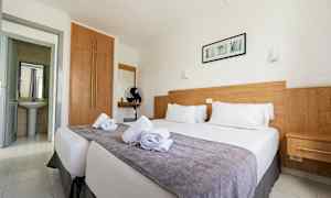 Kahden hengen huone sängyllä, puuyksityiskohtia ja valkoiset seinät. (Tekoälyn luoma teksti)