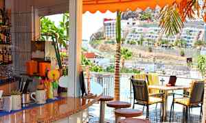 Kahvila, josta on näkymä aurinkoiselle tielle ja rakennuksille. (Tekoälyn luoma teksti)