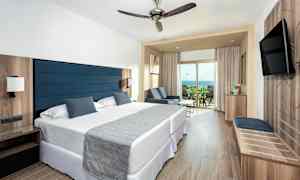 Hotellihuone, jossa on kaksi sänkyä, oleskelualue ja parveke merinäköalalla. (Tekoälyn luoma teksti)