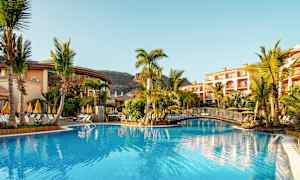 Uima-allasalue aurinkovarjoineen ja palmuineen hotellin läheisyydessä. (Tekoälyn luoma teksti)