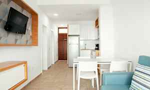 Moderni keittiö ja olohuone, joissa on vaalea sisustus, valkoiseksi maalatut seinät ja sininen sohva. (Tekoälyn luoma teksti)