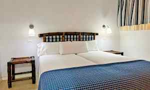 Makuuhuone, jossa on parivuode, siniruudullinen sängynpääty ja valkoiset vuodevaatteet. (Tekoälyn luoma teksti)