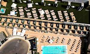 Ilmakuva hotellialueesta, jossa on uima-allas, aurinkotuoleja ja päivänvarjoja. (Tekoälyn luoma teksti)