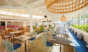 Avoin ravintola, jossa on pöytiä ja tuoleja sekä merinäköala. (Tekoälyn luoma teksti)