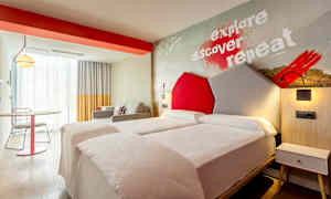 Moderni hotellihuone, jossa on kaksi yhden hengen vuodetta ja värikkäitä yksityiskohtia. (Tekoälyn luoma teksti)