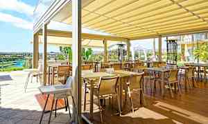 Terassi, jossa on useita pöytiä ja tuoleja markiisin alla. (Tekoälyn luoma teksti)