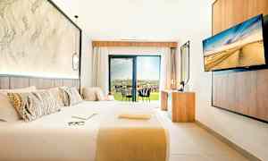 Moderni hotellihuone, jossa iso sänky, työpöytä ja näkymä terassille. (Tekoälyn luoma teksti)